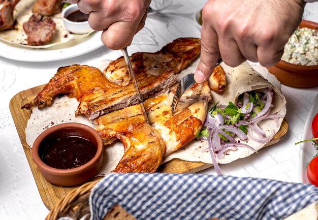 Top view a man cuts tobacco on pita bread with sauce and onions