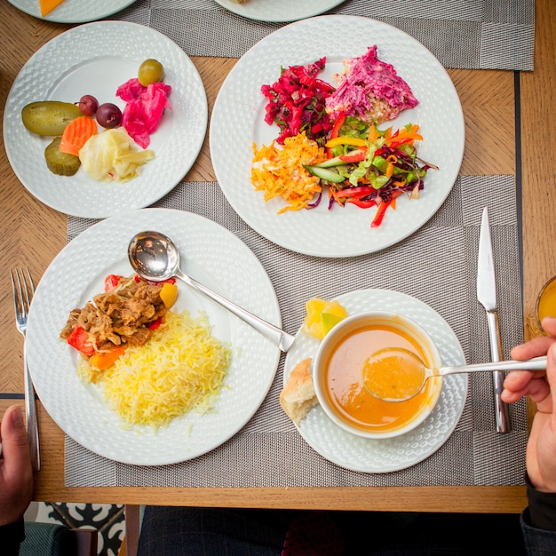 Foto gratuita riso della minestra mangiatrice di uomini di vista superiore con insalata della verdura e della carne sulla tavola