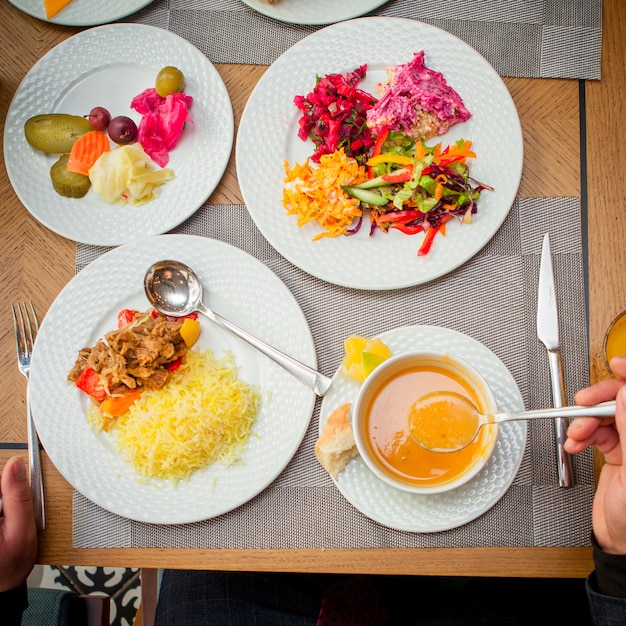 Free photo top view man eating soup rice with meat and vegetable salad on table