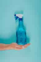 Free photo top view man holding cleaning solution on cyan blue