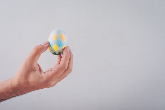 Top view man holding an easter egg on white background.