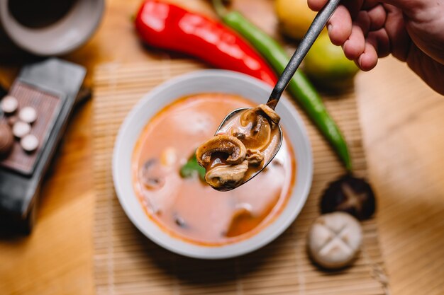 Top view man holds spoon of mushroom soup with mushrooms