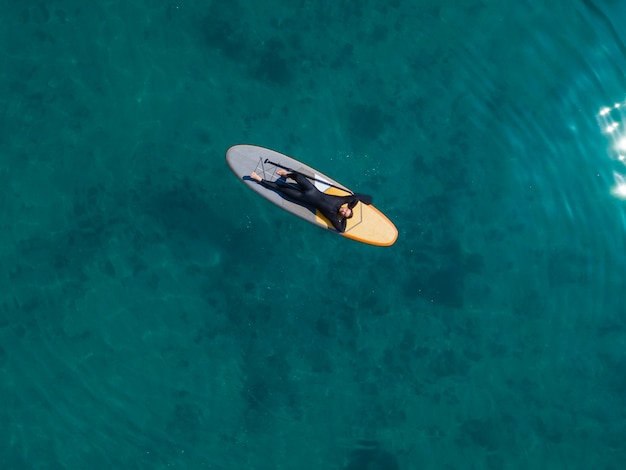 Top view man laying on surfboard