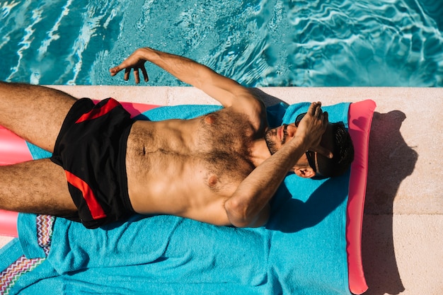 Top view of man relaxing next to pool