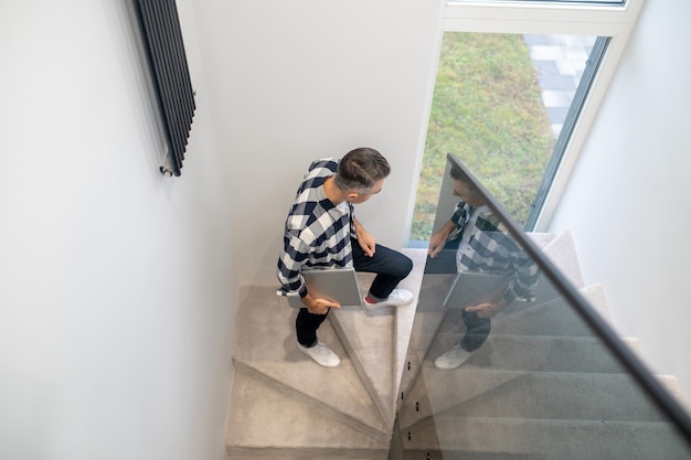 Free photo top view of man with laptop on stairs indoors