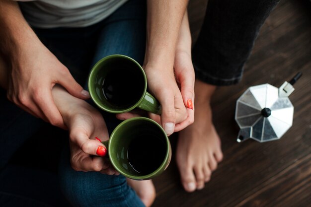 Top view man and woman holding cups with coffee