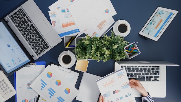 Top view of manager woman analyzing financial paperwork strategy typing expertise on laptop