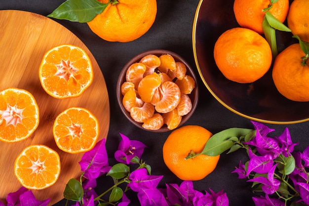 Free photo top view mandarin concept fresh mandarins and purple flowers