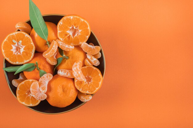 top view mandarins in plate with copy space on orange surface