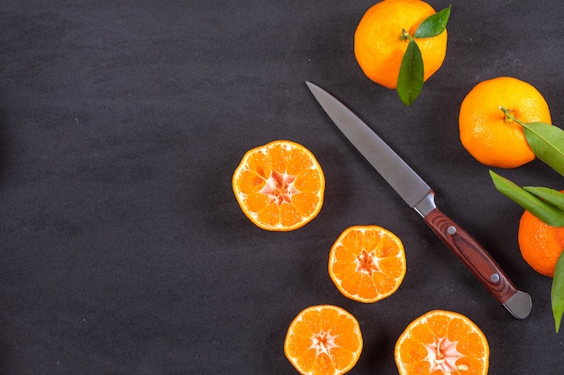 Top view mandarins with knife on black surface