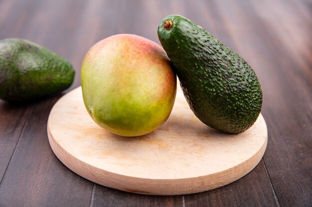 Top view of mango and avocado on a wooden kitchen board on a wooden surface