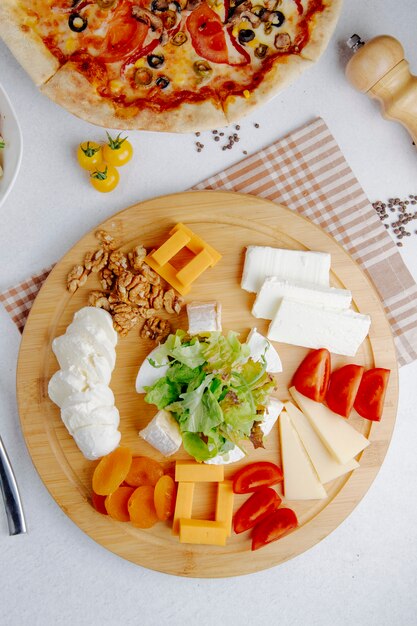 Top view of many sorts of cheese peaces served on wooden plate
