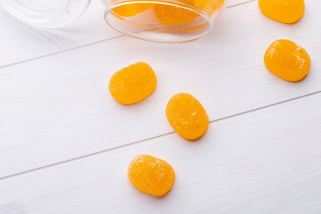 Top view of marmalade candies scattered from a glass on wooden surface
