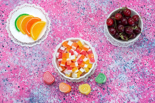 Top view marmalades and cherries on the colorful background color snack candy goody