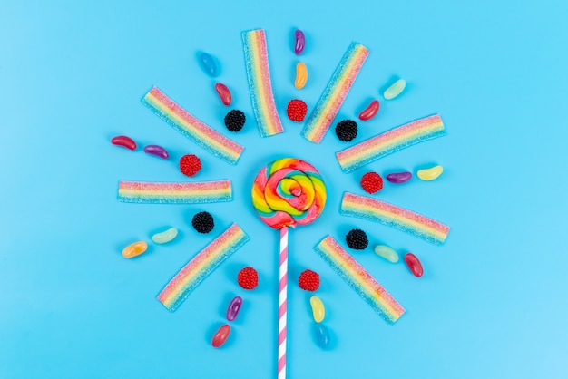 Free photo a top view marmalades and lollipops colorful delicious on blue, rainbow color sugar