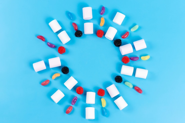 Free Photo a top view marshmallows and marmalades lined on blue, sugar confectionery children circle