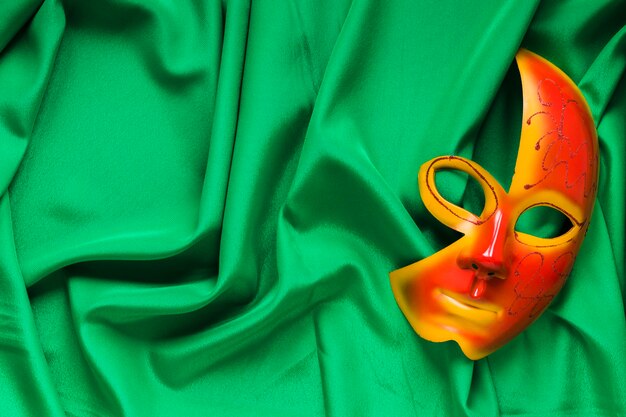 Вид сверху маски для карнавала на зеленой ткани