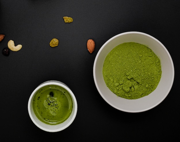 Top view of matcha tea powder in bowl with assortment of nuts