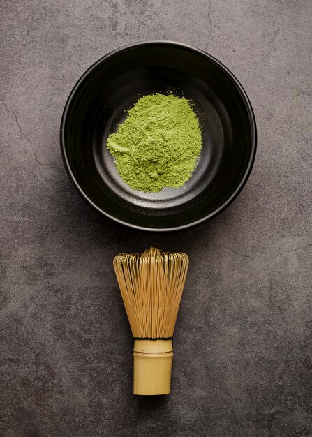 top view of matcha tea powder in bowl with bamboo whisk