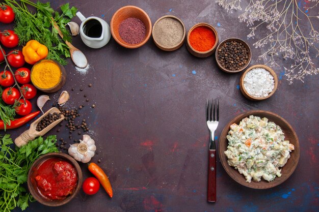 Top view mayyonaise salad with vegetables and seasonings on dark space