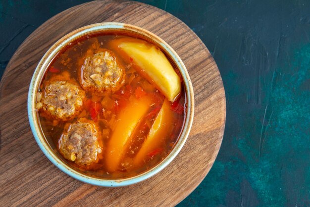 Top view meat balls soup with potatoes inside round plate on dark-blue surface