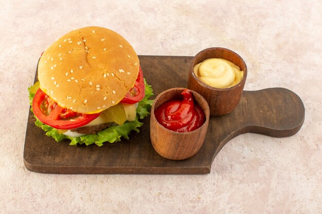 A top view meat burger with cheese and green salad along with ketchup and mustard