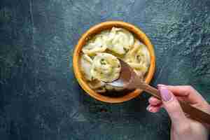 Free photo top view meat dumplings with female putting wooden spoon into it on dark surface