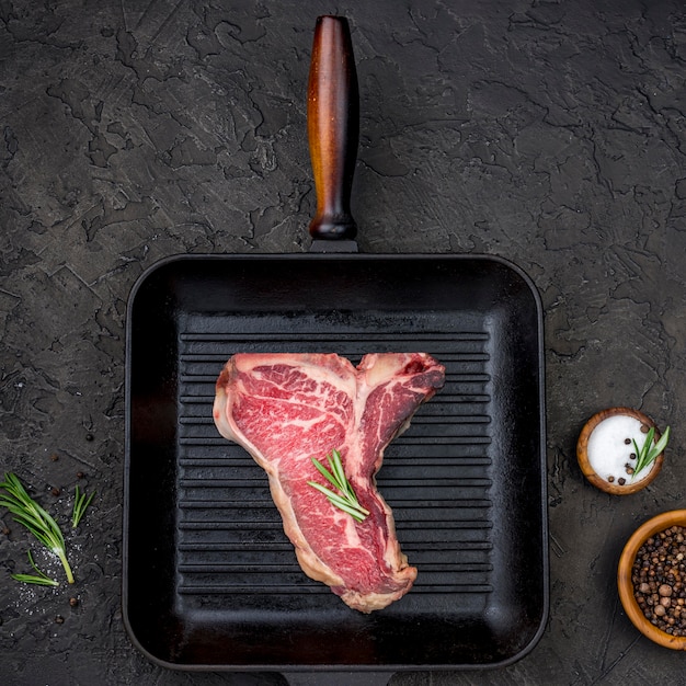 Top view of meat in pan with spices and herbs