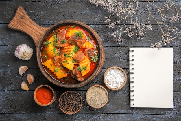 Vista dall'alto zuppa di ragù di carne con verdure e patate sulla scrivania scura