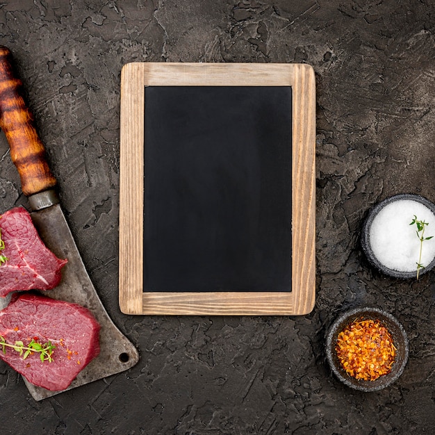 Top view of meat with cleaver and blackboard