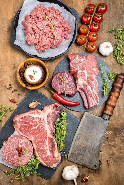 Top view of meat with cleaver and tomatoes