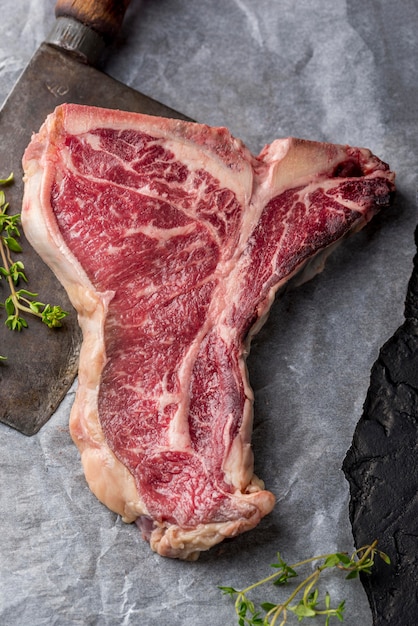 Top view of meat with herbs and cleaver