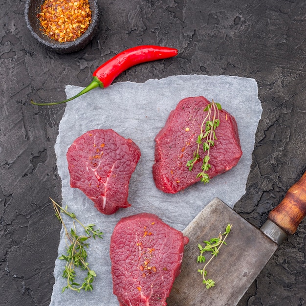 Top view of meat with herbs and cleaver