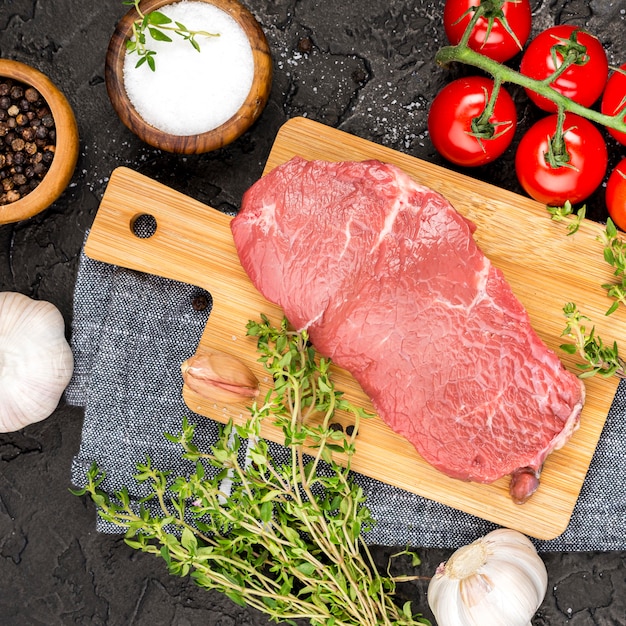 Top view of meat with herbs and tomatoes