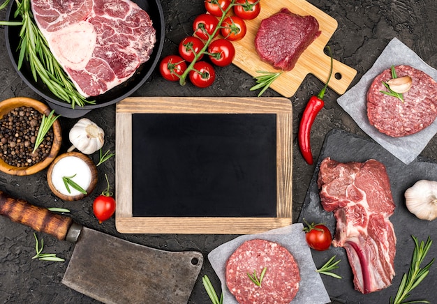 Top view of meat with tomatoes and blackboard