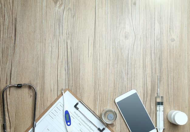 top view of medical examination report,cellphone,and medical equipments on wooden desk