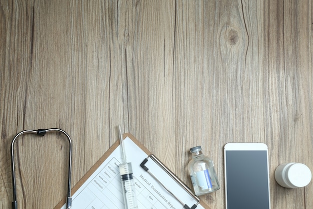 top view of medical examination report,cellphone,and medical equipments on wooden desk