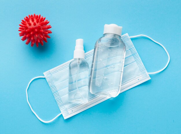 Top view of medical mask with hand sanitizer and virus