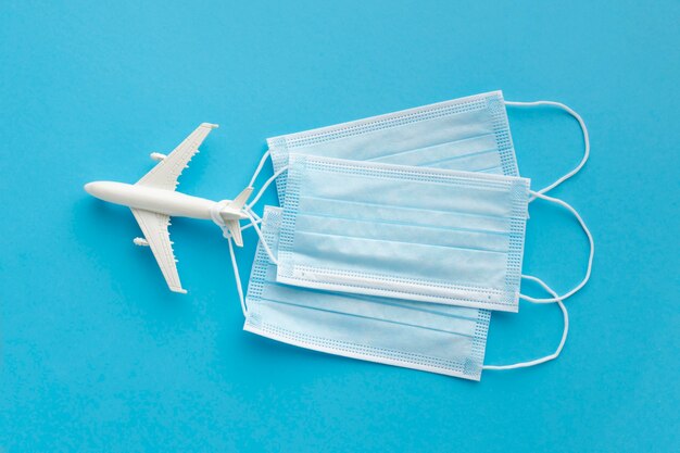 Top view of medical masks with airplane figurine