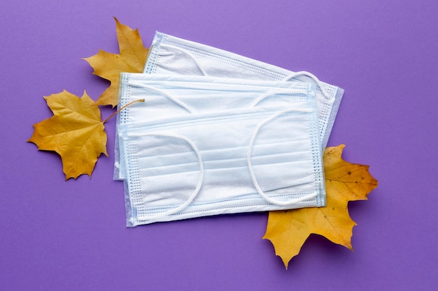 Top view of medical masks with autumn leaves