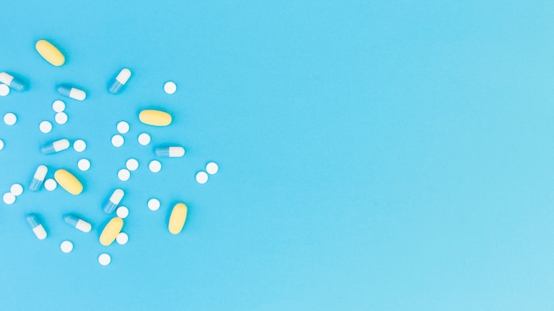 Top view of medical pills and capsules on blue background