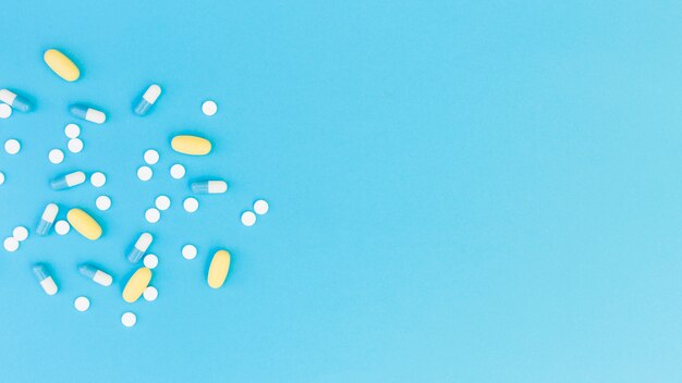 Top view of medical pills and capsules on blue background