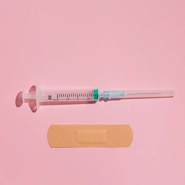 Free photo top view medical syringe with band aid