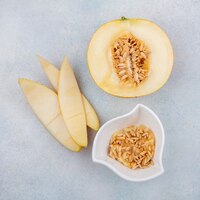 Vista dall'alto di melone con bucce con semi su una ciotola bianca su una superficie bianca