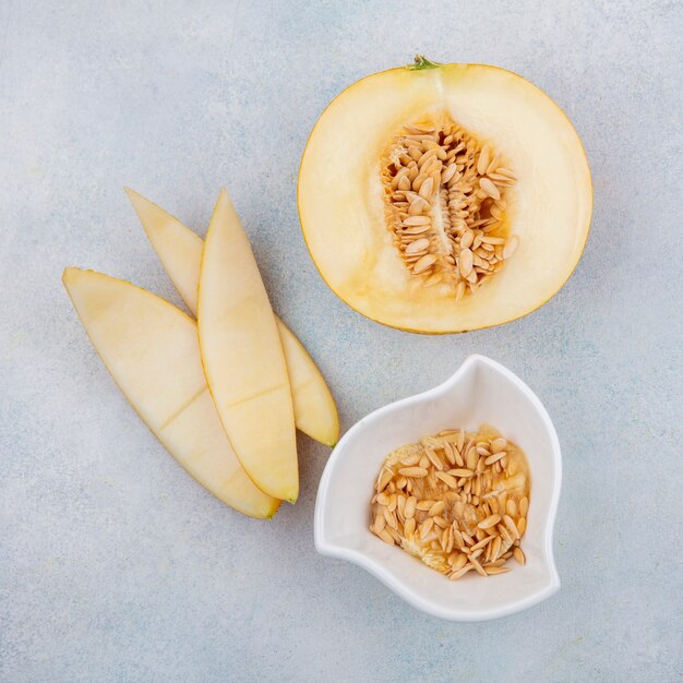 Top view of melon with peels with seeds on a white bowl on a white surface
