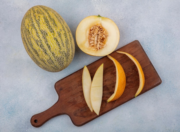 Top view of melon with peels on a wooden kitchen board on white surface
