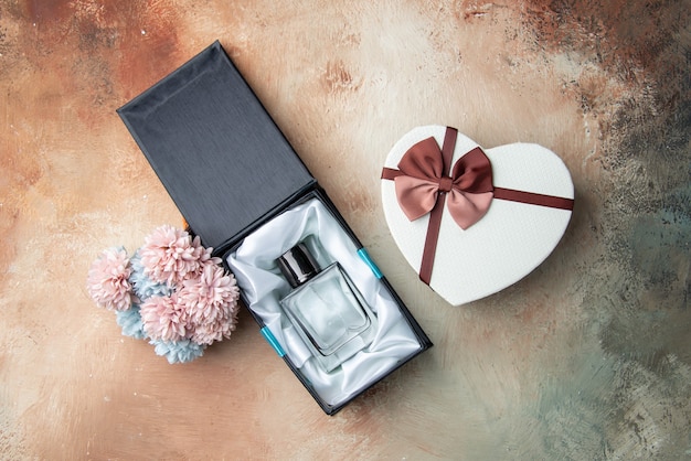 Free photo top view men cologne in box heart shaped box flowers on table