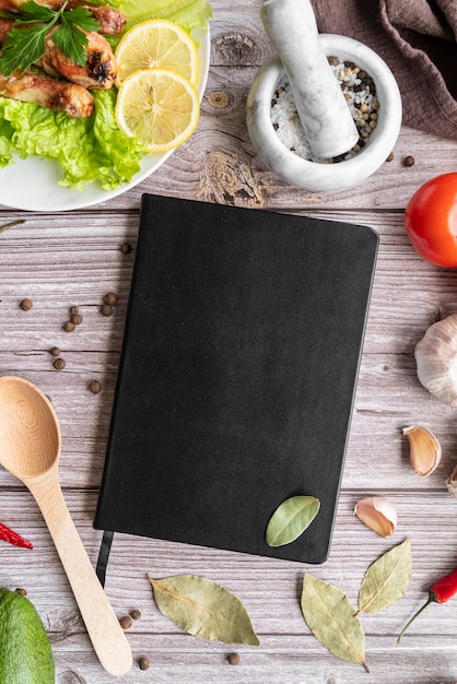 Top view of menu book with bay leaves and salad