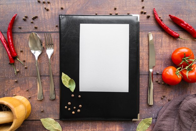 Top view of menu book with chili peppers and cutlery