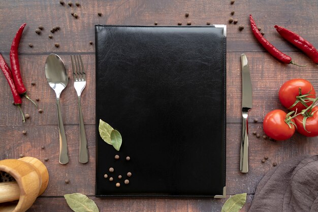 Top view of menu book with cutlery and chili peppers